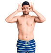 Young handsome man wearing swimwear trying to open eyes with fingers, sleepy and tired for morning fatigue