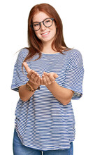 Young Read Head Woman Wearing Casual Clothes And Glasses Smiling With Hands Palms Together Receiving Or Giving Gesture. Hold And Protection