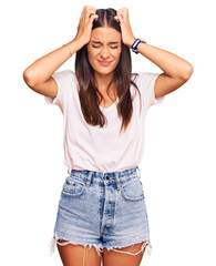 Wall Mural - Young hispanic woman wearing casual white tshirt suffering from headache desperate and stressed because pain and migraine. hands on head.