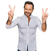 © Krakenimages.com - Middle age man wearing casual clothes smiling looking to the camera showing fingers doing victory sign. number two.