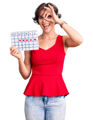 Sticker - Beautiful young woman with short hair holding heart calendar smiling happy doing ok sign with hand on eye looking through fingers