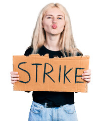 Poster - Young caucasian woman holding strike banner cardboard looking at the camera blowing a kiss being lovely and sexy. love expression.