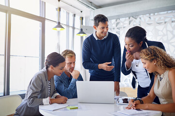 Canvas Print - His work is impressive. Shot of a group of coworkers working together on a laptop in an office.