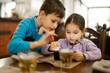 © AS Photo Family - Brother with sister play in smartphone together, while eat in restaurant.