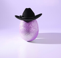 Easter Goes West: A Sparkling, Glittery Purple Easter Egg Wearing a Cowboy Hat on a Pastel Purple Background