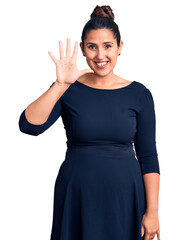 Poster - Young beautiful brunette woman wearing casual dress showing and pointing up with fingers number five while smiling confident and happy.