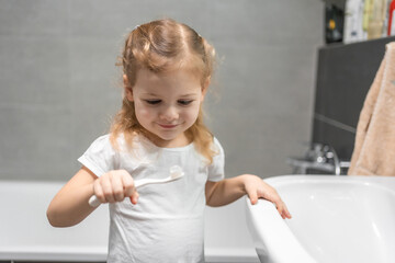 Wall Mural - Happy toddler girl brushing teeth in the bath