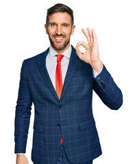 Handsome man with beard wearing business suit and tie smiling positive doing ok sign with hand and fingers. successful expression.