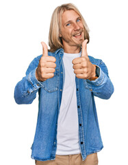 Poster - Caucasian man with blond long hair wearing casual denim jacket success sign doing positive gesture with hand, thumbs up smiling and happy. cheerful expression and winner gesture.