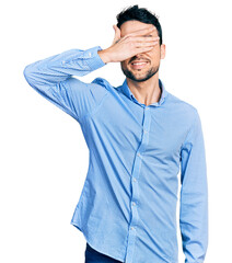 Poster - Hispanic man with beard wearing casual business shirt smiling and laughing with hand on face covering eyes for surprise. blind concept.