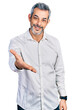 © Krakenimages.com - Middle age hispanic with grey hair wearing casual white shirt smiling cheerful offering palm hand giving assistance and acceptance.