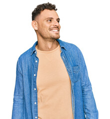 Sticker - Young hispanic man wearing casual clothes looking away to side with smile on face, natural expression. laughing confident.