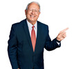 © Krakenimages.com - Senior man with grey hair wearing business suit and glasses with a big smile on face, pointing with hand finger to the side looking at the camera.