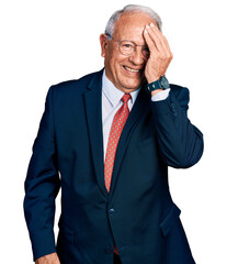 Wall Mural - Senior man with grey hair wearing business suit and glasses covering one eye with hand, confident smile on face and surprise emotion.