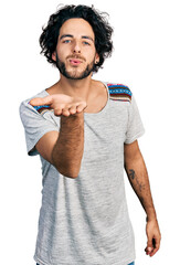 Canvas Print - Young hispanic man wearing casual t shirt looking at the camera blowing a kiss with hand on air being lovely and sexy. love expression.