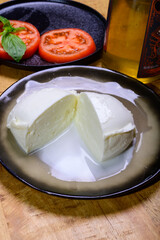 White ball of Italian soft cheese Mozzarella di Bufala Campana served with fresh green basil and red tomato