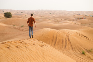 Wall Mural - A cheerful man enjoys a beautiful sunset on a hill in the desert. Happy summer holidays. An active lifestyle.