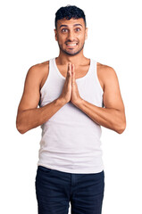 Canvas Print - Young hispanic man wearing casual clothes praying with hands together asking for forgiveness smiling confident.