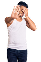 Poster - Young hispanic man wearing casual clothes covering eyes with hands and doing stop gesture with sad and fear expression. embarrassed and negative concept.