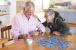 © Wavebreak Media - Happy senior diverse couple sitting at table and doing puzzles