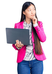 Sticker - Young beautiful chinese woman using laptop serious face thinking about question with hand on chin, thoughtful about confusing idea