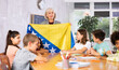 in geography lesson, students carefully listen to woman teacher who talks about Bosnia and Herzegovina