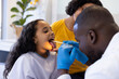 © Wavebreak Media - Happy diverse male doctor examining throat of girl with mother in hospital