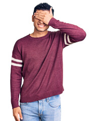 Sticker - Hispanic handsome young man wearing casual clothes smiling and laughing with hand on face covering eyes for surprise. blind concept.