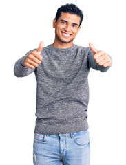 Sticker - Hispanic handsome young man wearing casual sweater approving doing positive gesture with hand, thumbs up smiling and happy for success. winner gesture.