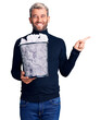 © Krakenimages.com - Young handsome blond man holding paper bin with crumpled papers smiling happy pointing with hand and finger to the side