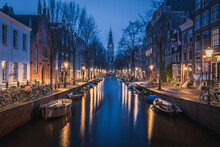 Evening Panoramic View Of The Famous Historic Center With Lights, Bridges, Canals And Traditional Dutch Houses In Amsterdam, Netherlands