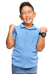 Canvas Print - Little boy hispanic kid wearing casual clothes excited for success with arms raised and eyes closed celebrating victory smiling. winner concept.