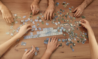 Poster - Jigsaw solutions. Shot of a group of people building a puzzle together.