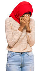 Wall Mural - Young african american woman wearing traditional islamic hijab scarf with sad expression covering face with hands while crying. depression concept.