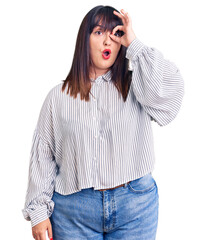 Poster - Young plus size woman wearing casual clothes doing ok gesture shocked with surprised face, eye looking through fingers. unbelieving expression.