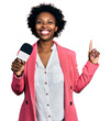 © Krakenimages.com - African american woman with afro hair holding reporter microphone surprised with an idea or question pointing finger with happy face, number one