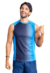 Canvas Print - Handsome hispanic man wearing sportswear smiling with happy face looking and pointing to the side with thumb up.