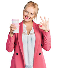 Canvas Print - Young blonde woman wearing business clothes and drinking coffee doing ok sign with fingers, smiling friendly gesturing excellent symbol