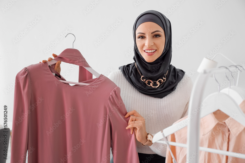 Beautiful Muslim woman with clothes at home