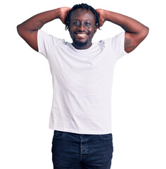 Sticker - Young african american man with braids wearing casual white tshirt relaxing and stretching, arms and hands behind head and neck smiling happy