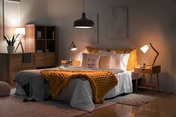 Wall Mural - Interior of bedroom with knitted plaid on bed and glowing lamps at night