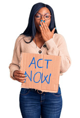 Poster - Young african american woman holding act now banner covering mouth with hand, shocked and afraid for mistake. surprised expression