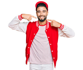 Wall Mural - Young man with beard wearing baseball uniform smiling cheerful showing and pointing with fingers teeth and mouth. dental health concept.