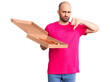 Young handsome man holding delivery pizza cardboard box with angry face, negative sign showing dislike with thumbs down, rejection concept