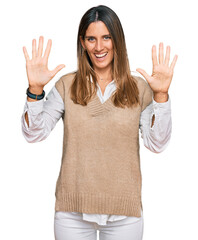 Wall Mural - Young woman wearing casual clothes showing and pointing up with fingers number ten while smiling confident and happy.