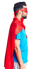 Young handsome man with beard wearing super hero costume looking to side, relax profile pose with natural face with confident smile.