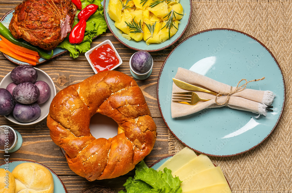 Tasty dishes and painted eggs for Easter dinner on wooden background, closeup