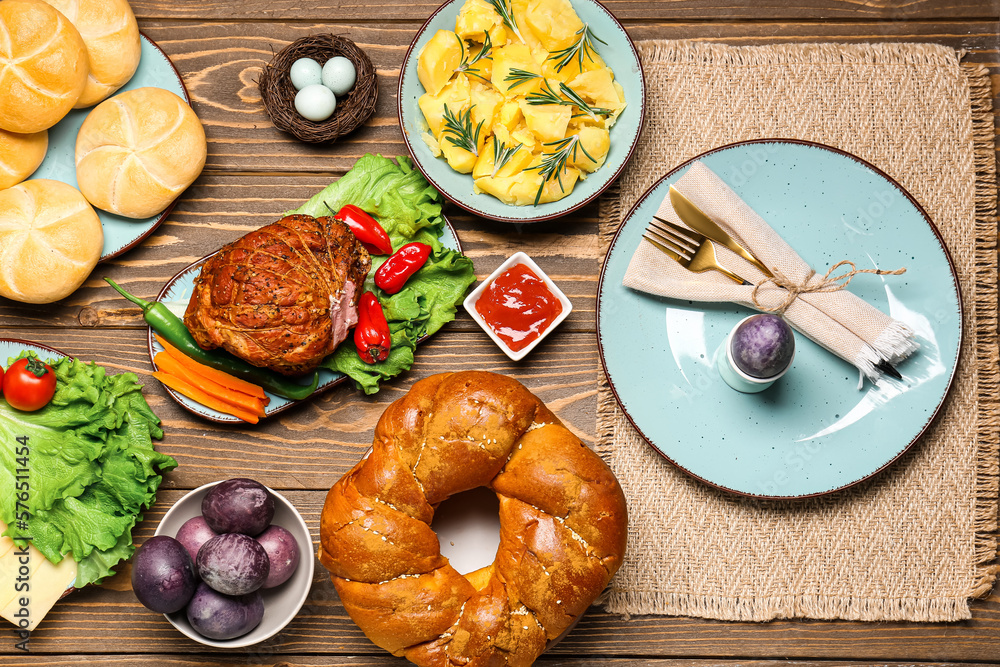 Tasty dishes and painted eggs for Easter dinner on wooden background