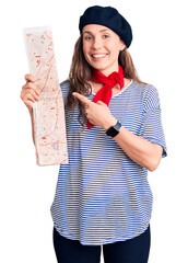 Poster - Young beautiful blonde woman wearing french beret holding city map smiling happy pointing with hand and finger