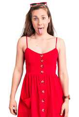 Poster - Young beautiful blonde woman wearing casual dress sticking tongue out happy with funny expression. emotion concept.